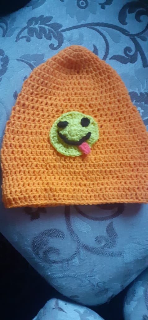 Sunshine Smile Beanie — an orange crocheted beanie with a green smiley patch