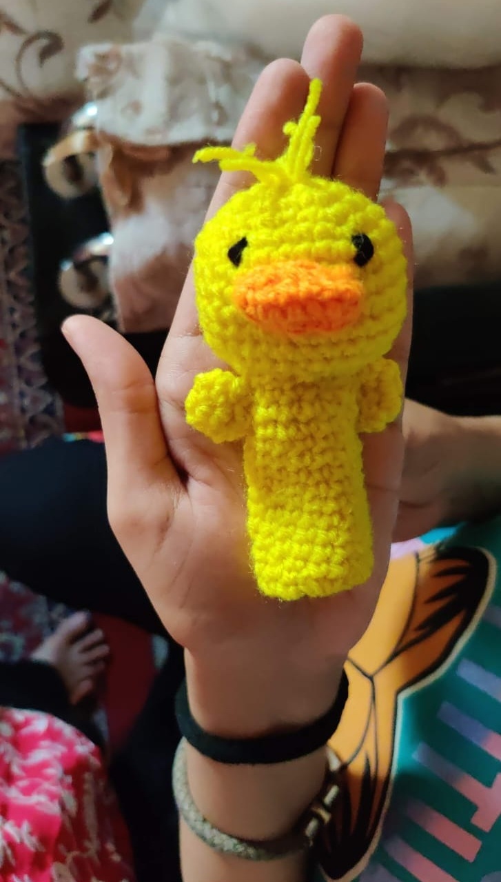 Sunny the Duck — a bright yellow crocheted duck finger puppet with an orange beak
