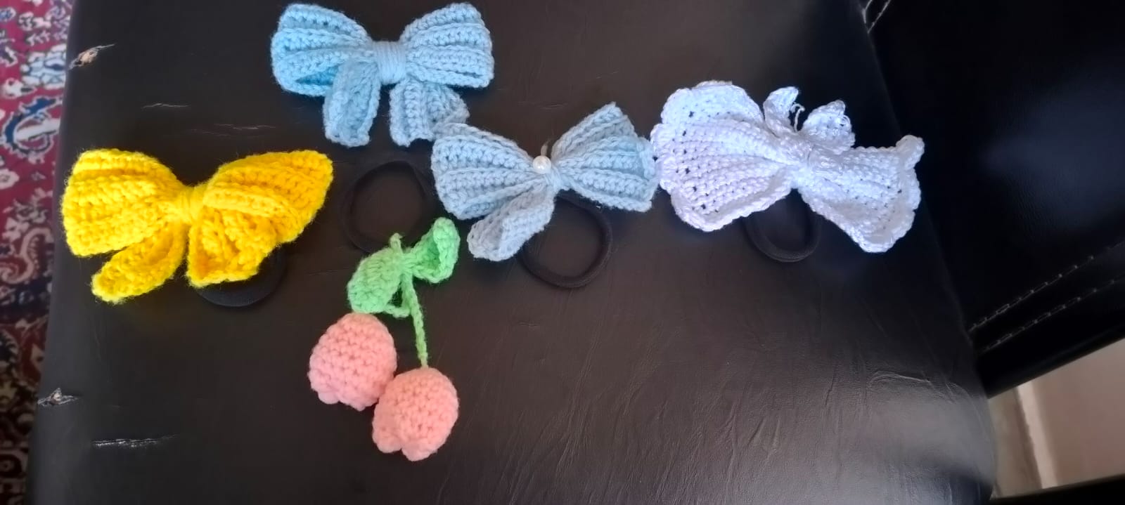 Hair Accessories — a set of crocheted hair bows in yellow, blue and white on elastic ties, with a small pink cherry pair