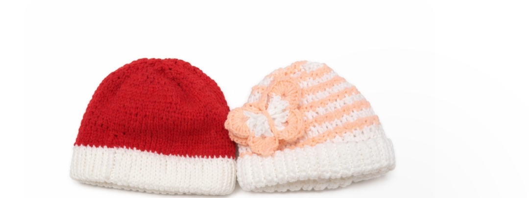 Cosy Pair Beanies — two crocheted beanies, one in red and white, the other in peach with a butterfly accent