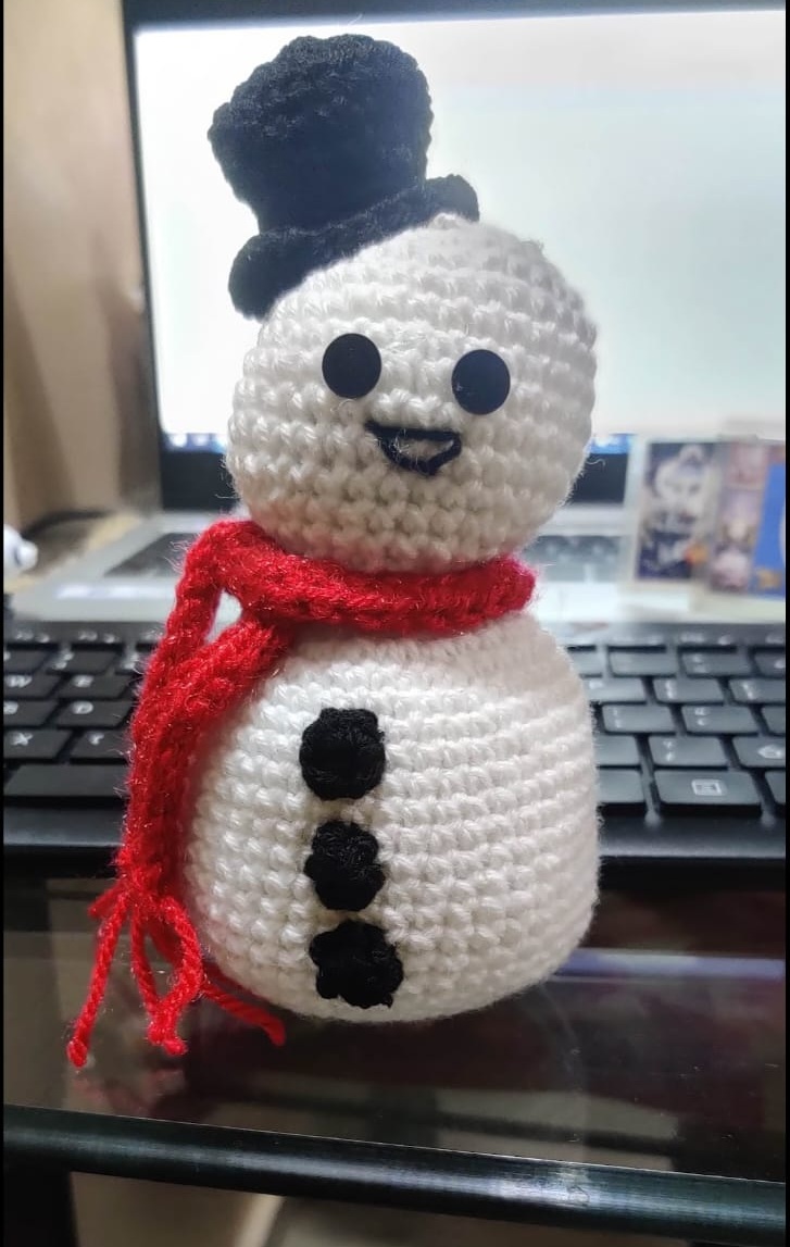 Frosty the Snowman — a white crocheted snowman with a black top hat, red scarf and three black buttons