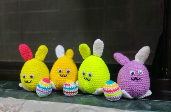 The Bunny Egg Family — four colourful crocheted bunny eggs in yellow, lime and lavender, with little painted decorative eggs