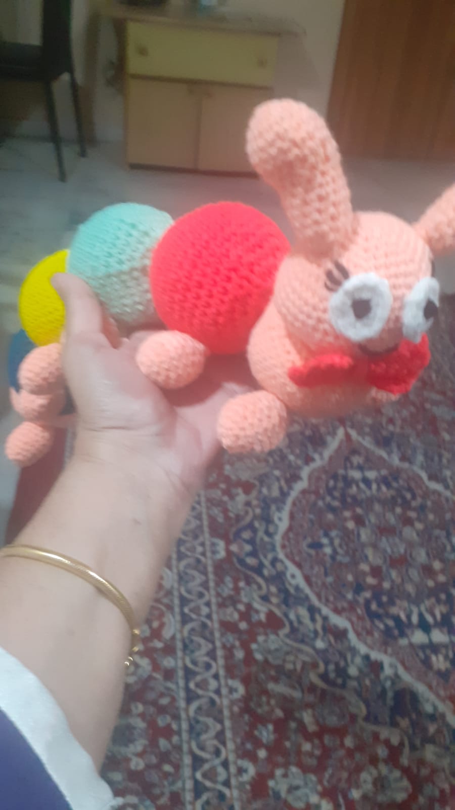 Coral the Caterpillar — a peach and pastel crocheted caterpillar with big eyes and a smiling face