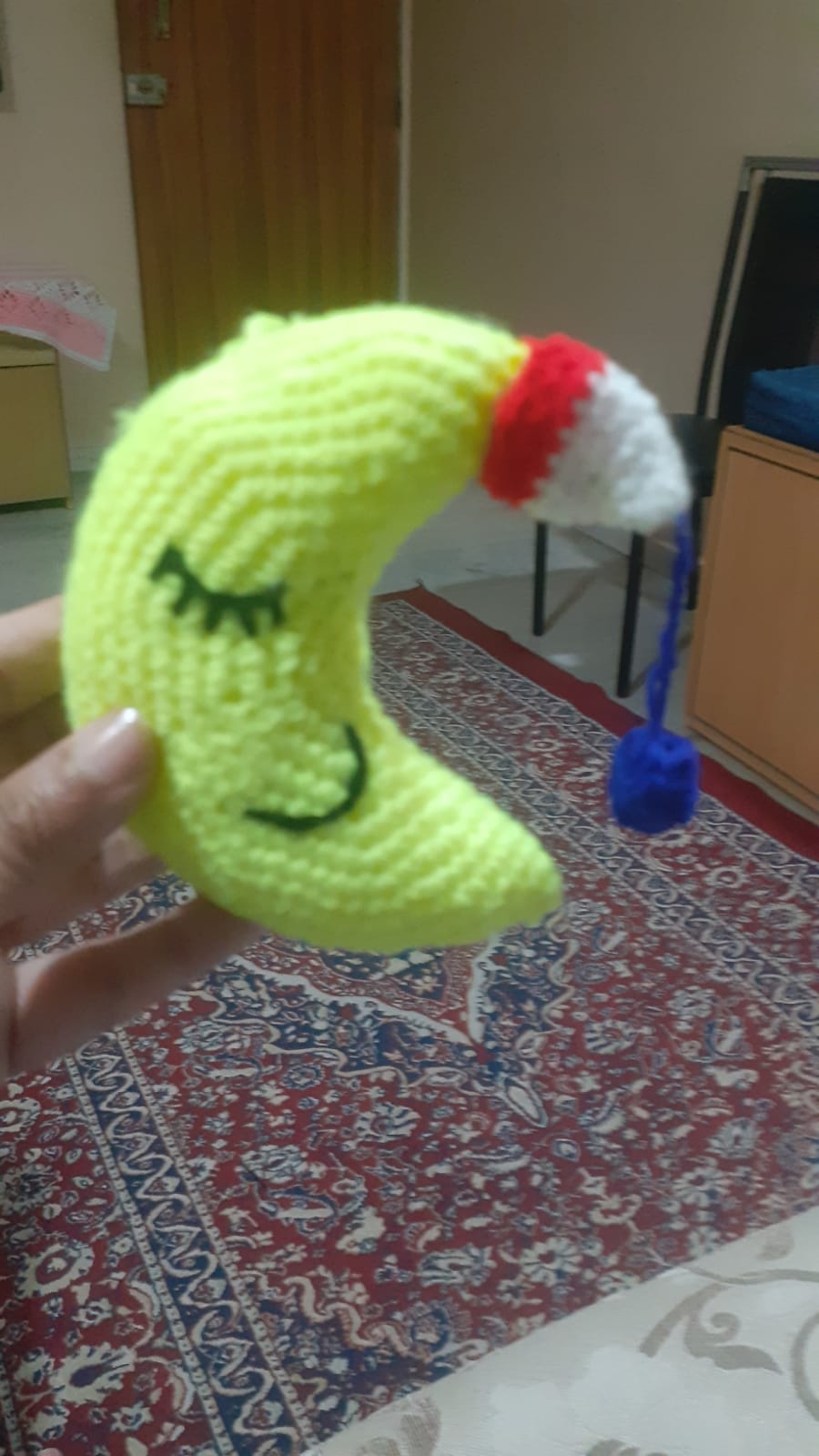 Luna the Sleepy Moon — a crocheted crescent moon with closed eyes and a tiny Santa hat